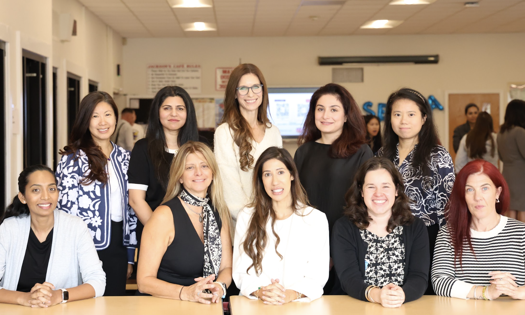 A diverse group of ten women pose together in a brightly lit indoor room.